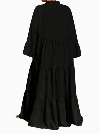 Linen & Loom black midi tunic dress with long sleeves and tiered trapeze hem, worn by a model in a studio setting.