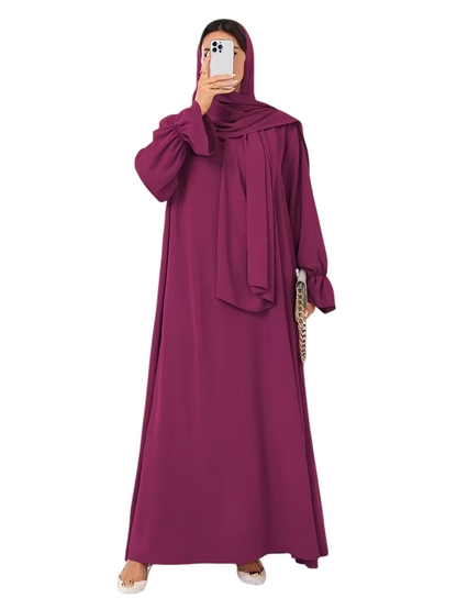 Linen & Loom elegant deep magenta one-piece abaya with flowing bell sleeves and matching hijab in a bright room.