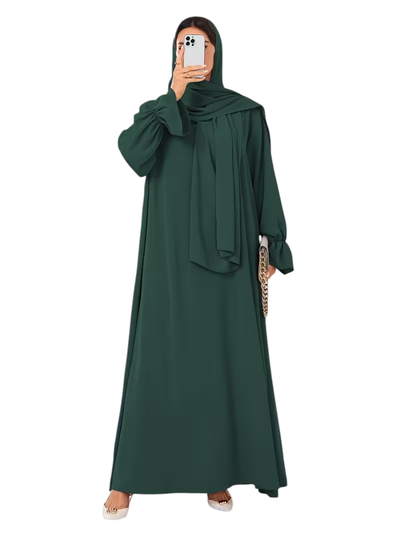 Linen & Loom dark green one-piece abaya with elegant bell sleeves and matching hijab, worn by a woman in a bright room.