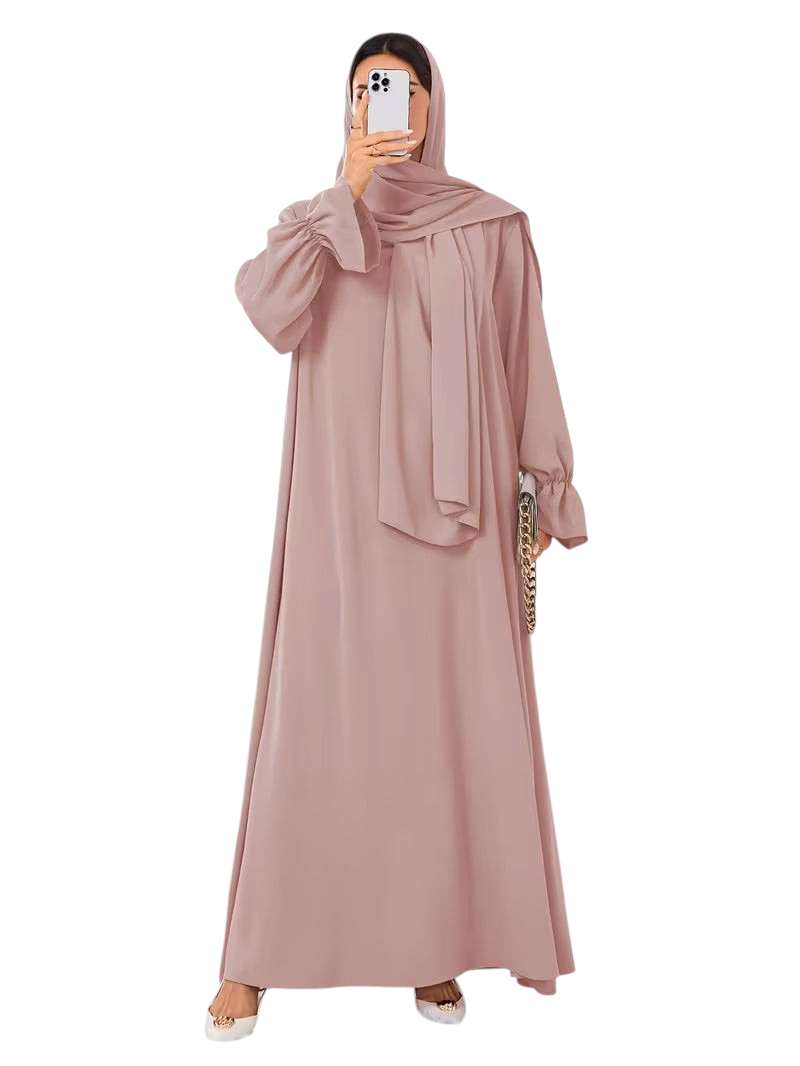 Linen & Loom dusty pink one-piece abaya with elegant bell sleeves and a flowing modest silhouette on a woman.