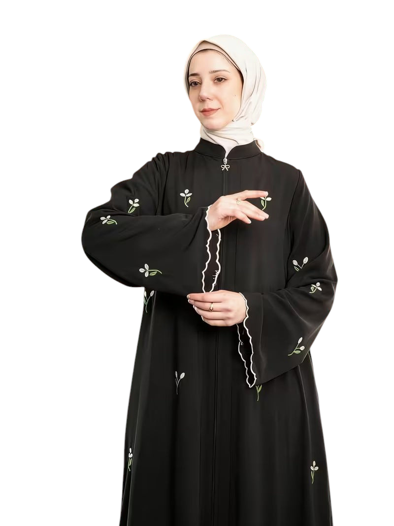 Linen & Loom black abaya featuring delicate white floral embroidery, front zipper, and scalloped sleeve cuffs.