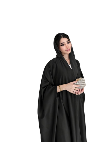 Linen & Loom black batwing sleeve abaya gown worn by a woman with a matching hijab and a small embellished clutch