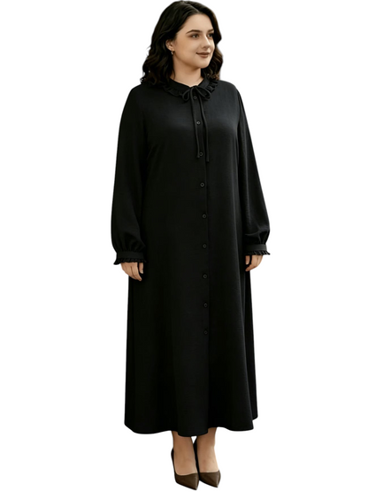 Linen & Loom black ruffle abaya dress with a round neckline, long sleeves, and drawstring waist on a woman outdoors.