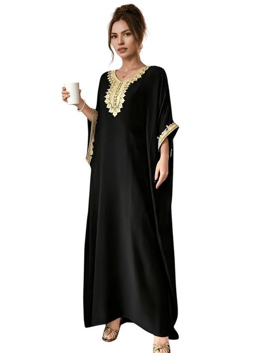 Linen & Loom black batwing abaya with intricate golden embroidery on the neckline and cuffs, worn in a cafe setting.