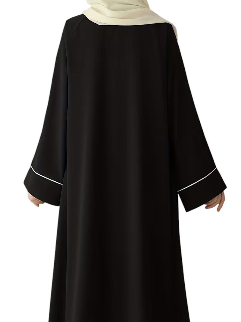 Linen & Loom black abaya with white sleeve trim and a matching hijab, featuring a loose, modest, full-length fit.
