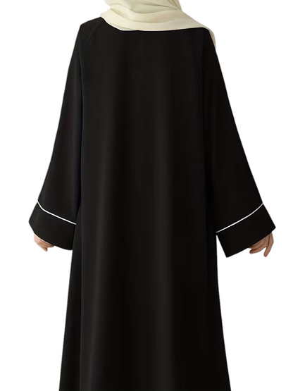 Linen & Loom black abaya with white sleeve trim and a matching hijab, featuring a loose, modest, full-length fit.