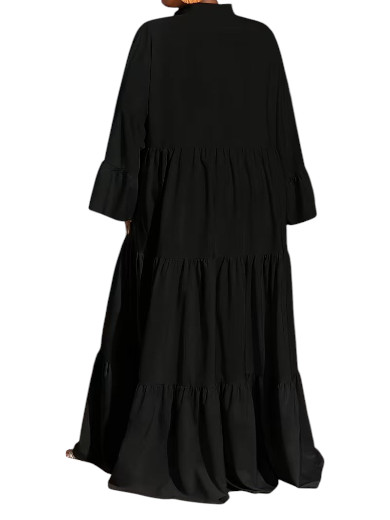 Linen & Loom black tiered maxi dress with long sleeves and a loose fit, shown from the back in a modern room.