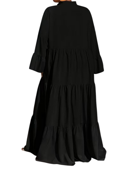 Linen & Loom black tiered maxi dress with long sleeves and a loose fit, shown from the back in a modern room.
