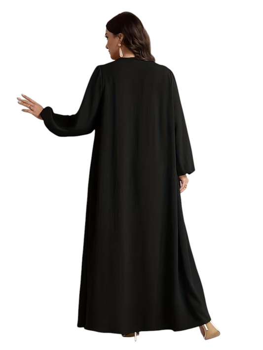 Linen & Loom plus size black long sleeve modest dress with a flowing silhouette worn by a woman in an arched doorway