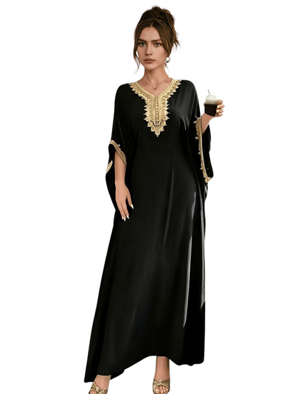Linen & Loom black batwing abaya with intricate golden embroidery on the neckline and cuffs in a cafe setting